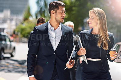 Buy stock photo Shot of corporate colleagues having a discussion while walking down the street