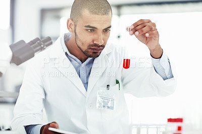 Buy stock photo Shot of a male scientist examining a test tube filled with blood