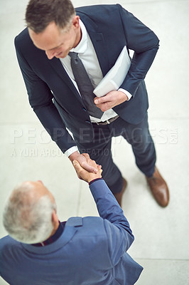 Buy stock photo High angle shot of two businessmen shaking hands in an office