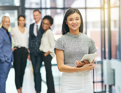 Buy stock photo Portrait of a young businesswoman holding a digital tablet with her colleagues in the background