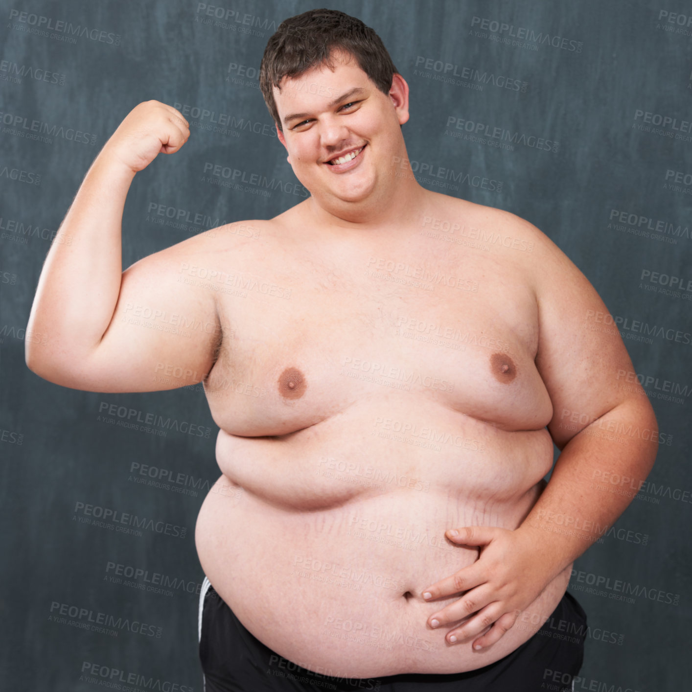 Studio shot of an obese young shirtless man flexing his bicep - stock photo...