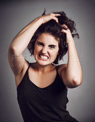 Pics of Studio portrait of a young woman pulling her hair with rage while standing against a grey background, stock photo, images and stock photography PeopleImages.com. Picture 1891023