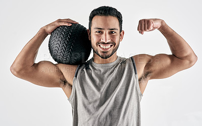Buy stock photo Studio portrait of a muscular young man flexing while holding an exercise ball against a white background