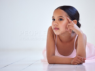 Buy stock photo Shot of a little girl looking thoughtful while lying on the floor in a ballet studio