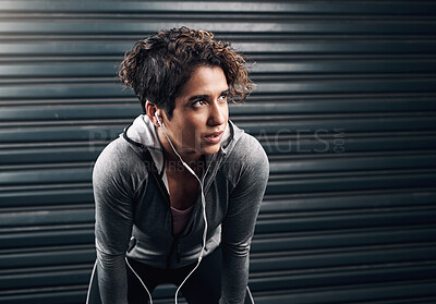 Buy stock photo Shot of a young woman taking a break and catching a breather while exercising outside against a black background