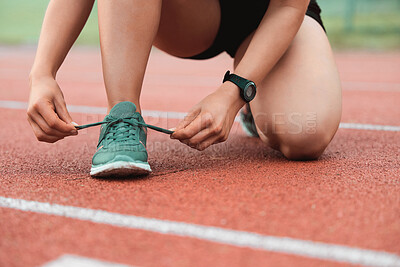 Buy stock photo Cropped shot of an unrecognizable sportswoman tying her laces out on track