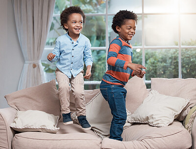 Buy stock photo Shot of two little boys jumping on a sofa at home