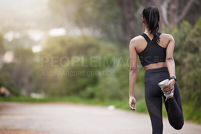 Buy stock photo Rearview shot of a sporty young woman stretching her legs while exercising outdoors