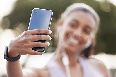 Buy stock photo Closeup shot of a sporty young woman wearing earphones and taking selfies while exercising outdoors