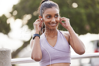Buy stock photo Shot of a sporty young woman wearing earphones while exercising outdoors