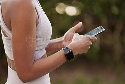 Buy stock photo Closeup shot of an unrecognisable woman using a cellphone while exercising outdoors