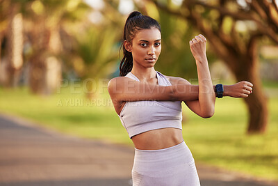 Buy stock photo Portrait of a sporty young woman stretching her arms while exercising outdoors