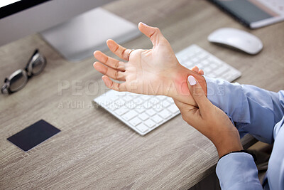 Buy stock photo Cropped shot of an unrecognisable businesswoman sitting alone in the office and suffering from wrist pain