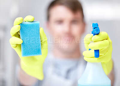 Buy stock photo Shot of a young man holding a spray bottle of detergent and a sponge