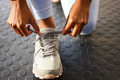 Buy stock photo Shot of an unrecognizable woman tying her shoelaces before a workout in the gym