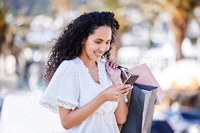 Buy stock photo Shot of a young woman using a smartphone while shopping against an urban background