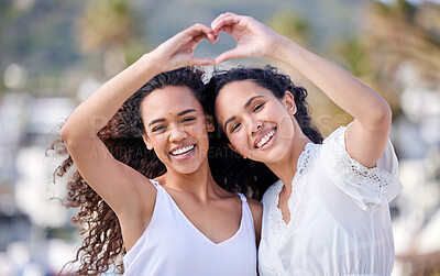 Buy stock photo Shot of two young women making a heart shaped gesture during a fun day outdoors