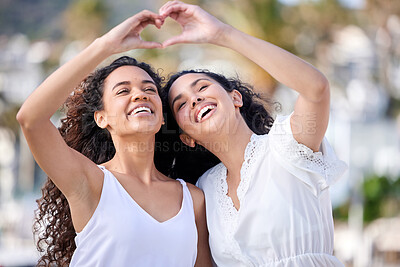 Buy stock photo Shot of two young women making a heart shaped gesture during a fun day outdoors