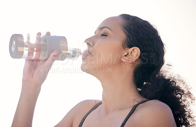 Buy stock photo Cropped shot of a fit young woman drinking water while out for a workout