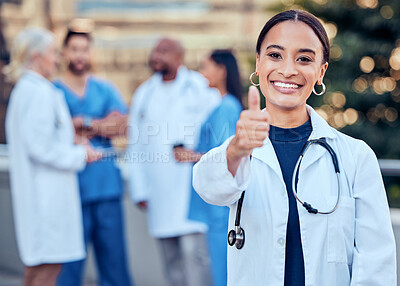 Buy stock photo Shot of a young female doctor showing a thumbs up in the city
