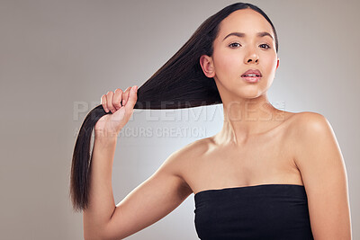 Buy stock photo Shot of an attractive young woman posing alone in the studio and holding her hair