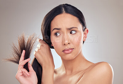 Buy stock photo Shot of an attractive young woman holding her hair and looking worried while posing in the studio