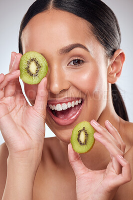 Buy stock photo Studio portrait of a beautiful young woman posing with kiwi against a grey background