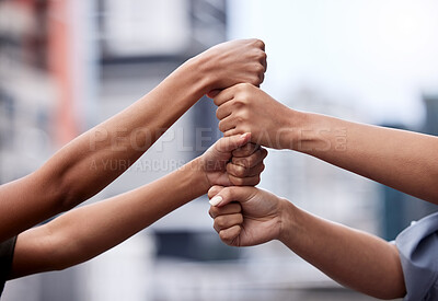Buy stock photo Cropped shot of a group of unrecognizable businesspeople stacking fists against a city background