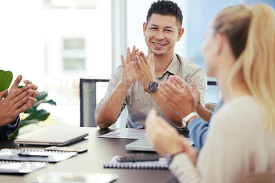 Buy stock photo Shot of a young businessman applauding while sitting alongside his colleagues during a presentation in an office