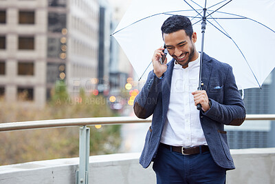 Buy stock photo Cropped shot of a handsome young businessman making a phonecall while standing outside with an umbrella in the city
