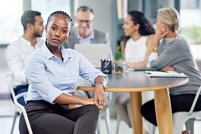 Buy stock photo Shot of a young businesswoman sitting in an office with her colleagues in the background