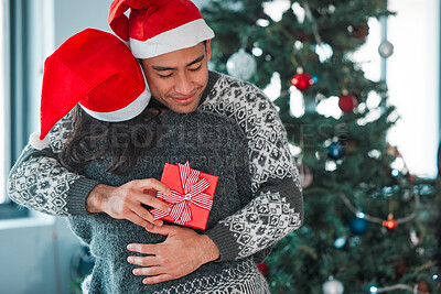 Buy stock photo Shot of a young couple hugging while exchanging gifts at home