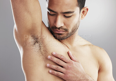 Buy stock photo Cropped studio shot of a muscular young man sniffing his armpit against a grey background