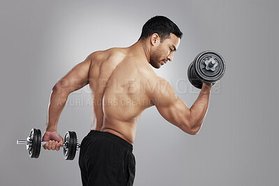 Buy stock photo Studio shot of a young man practicing his bicep curls against a grey background