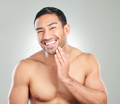 Buy stock photo Studio shot of a handsome young man touching his face against a grey background