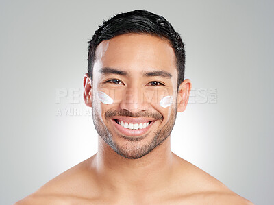 Buy stock photo Studio shot of a handsome young man applying moisturiser against a grey background