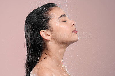 Buy stock photo Shot of a young woman washing her hair in a shower against a studio background