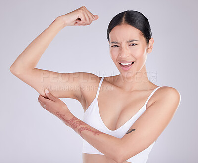 Buy stock photo Shot of an attractive young woman standing and tugging at excess skin on her arm