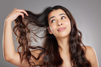 Buy stock photo Studio shot of an attractive young woman holding her hair against a grey background