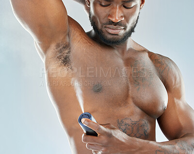 Buy stock photo Studio shot of a muscular young man spraying himself with deodorant