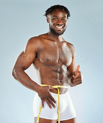 Buy stock photo Studio shot of an athletic young man measuring his waist
