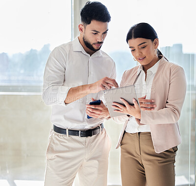 Buy stock photo Cropped shot of two young businesspeople looking at a tablet while standing in their office