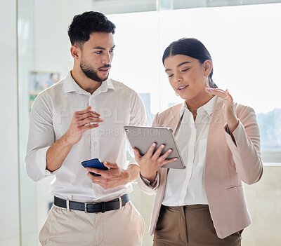 Buy stock photo Cropped shot of two young businesspeople looking at a tablet while standing in their office