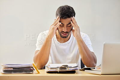 Buy stock photo Shot of a handsome young man sitting alone and feeling stressed while working from home