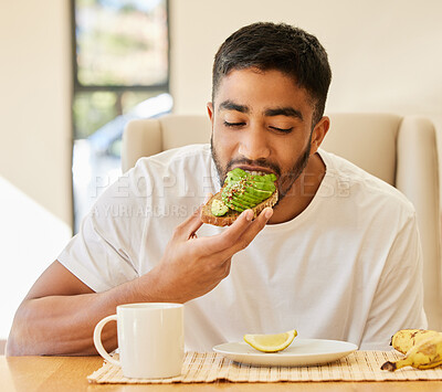 Buy stock photo Shot of a handsome young man sitting alone and having breakfast at home