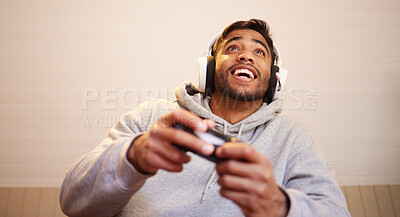 Buy stock photo Shot of a handsome young man sitting alone at home and playing video games