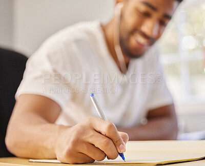 Buy stock photo Shot of an unrecognisable man sitting alone at home and writing in a book