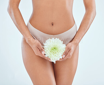 Buy stock photo Cropped shot of an unrecognisable woman standing alone in the studio and posing while holding a flower