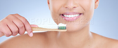 Buy stock photo Cropped studio shot of a young woman brushing her teeth against a blue background