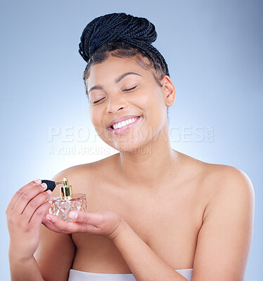 Buy stock photo Studio shot of an attractive young woman using using perfume against a blue background